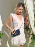 Woman in a white dress holding a blue Elyse & i clutch outdoors