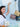 Woman holding a gold Elyse & i Otis handbag with gold chain, surrounded by other Otis handbags on a light blue background