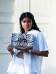 Woman in white holding an Elyse & i Theo Knot bag in snakeprint monochrome leather.