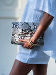 Woman in white holding monchrome snakeprint leather bag by Elyse & i called Theo Knot.