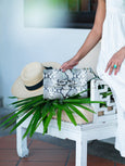 Theo Knot shoulder bag by Elyse & i on chair with hat and leaves.