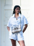 Model in white top and shorts wearing a bag by Elyse & i as a crossbody, called Theo Knot.