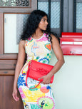 Woman holding a red Theo Knot handbag by Elyse & i in front of a wooden door with glass panels.