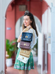 Woman holding multiple Elyse & i Otis handbags in front of a red door