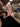Woman holding a drink in a bar setting with bookshelves in the background and a monochrome snakeprint handbag with shell detail - the Otis by Elyse & i.