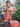 Woman in a peach outfit with a blue Elyse & i Otis handbag seated outdoors.
