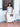 Woman in a white dress holding a cheetah print Finn Scallop clutch by Elyse & i on a tiled floor.