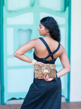 Woman holding a cheetah print Finn Scallop clutch by Elyse & i against a teal wall