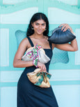 Woman holding three Dawn Scallop leather bags by Elyse & i with colourful bows against a light blue background