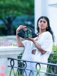 Woman holding a black Elyse & i Dawn bow handbag with a Fleur Kakasi tiger palm silk scarf tied onto it.