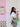 Woman holding flowers and a gold Elyse & i Dawn Scallop clutch in front of a pink wall with a white door.