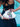 Person holding a silver croco embossed leather Dawn Scallop bag with bowwith floral accents by Elyse & i against a blue background