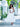 Woman in a white dress holding a leafy plant in an outdoor setting clutching a silver croco embossed leather Dawn Scallop bag by Elyse & i