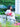 Woman in white outfit holding a red Elyse & i Finn Scallop clutch in an outdoor setting with greenery.