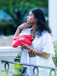 Woman holding a red Elyse & i Finn Scallop handbag outdoors with blurred background