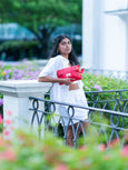 Woman holding a red Elyse & i Finn Scallop bag in a garden setting