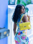 Woman holding a yellow Finn Elyse & i handbag against a blue wall