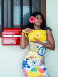 Woman holding a yellow Finn Elyse & i clutch bag in front of a red toolbox.