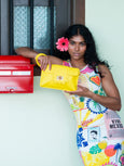 Woman holding a yellow Finn Elyse & i handbag in front of a colorful background