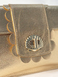 Gold metallic clutch bag with decorative emblem on a white background