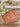 Pink Elyse & i Finn Scallop handbag with gold accents on a wooden surface with flowers in the background