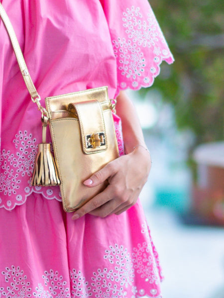 Elyse & i gold phone bag, the Luna Lock, worn as crossbody on model with pink coord set.