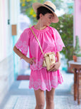 Girl in pink coord wearing a crossbody bag in gold leather called the Luna by Elyse & i. She's wearing a hat.