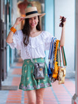 Woman holding multiple Elyse & i Luna Lock handbags and wearing a white blouse and green skirt.