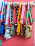 Collection of colorful Elyse & i Luna Phone handbags with straps on a red background