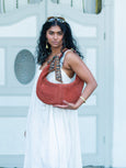 Woman holding a terracotta Elyse & i Martha hobo handbag in front of a white door