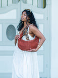 Woman holding a brown Elyse & i Martha hobo handbag with a patterned strap against a light background