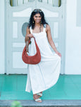 Woman in a white dress holding a brown Elyse & i Martha Suede Hobo bag in terracotta suede against a light blue wall.