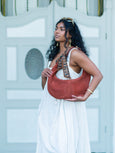 Woman holding a terracotta Elyse & i Martha hobo handbag against a light blue wall
