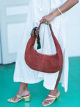 Person holding a brown Elyse & i Martha hobo suede handbag with a white background