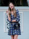 Model wearing Elyse & i Nell Knot bag in black nappa leather with gold knot detail, styled crossbody with blue patterned dress.