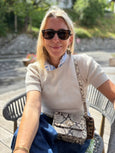 Woman sitting outdoors wearing sunglasses and a snake print patterned handbag by Elyse & i