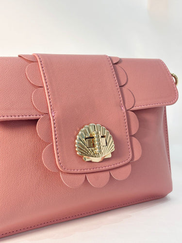 Pink Finn Scallop handbag with shell design clasp on a light background