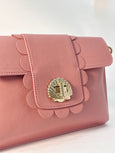Pink Finn Scallop handbag with shell design clasp on a light background