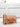 Tan handbag with a gold chain on a white surface