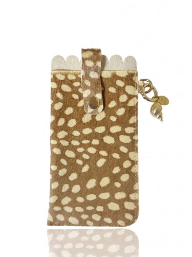 A small brown and cream spotted glasses case with a flap closure, shown on a white background with a faint reflection below. A small gold-toned charm hangs from the side.