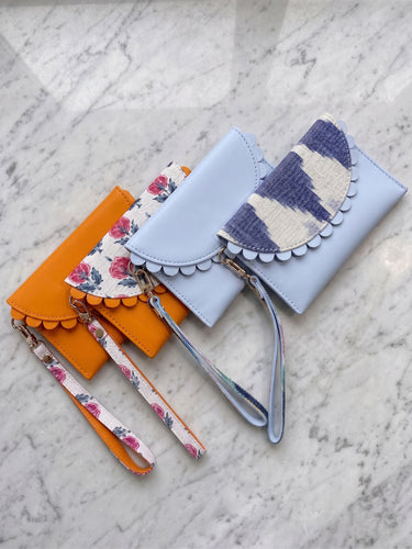 Three colorful wallets with wristlets on a marble surface