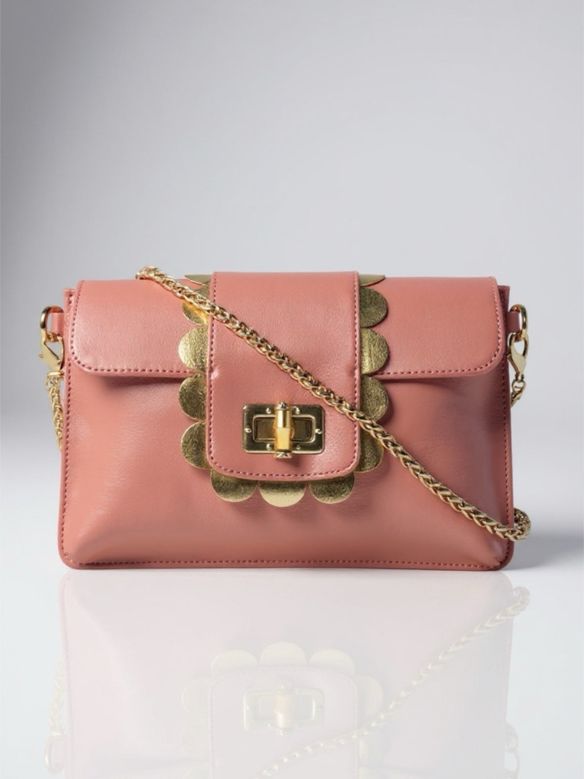 Pink handbag with gold chain strap on a light gray background