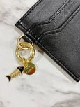 Black wallet with a gold fish charm on a marble surface