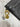 Black leather wallet with gold and silver charm on a marble surface