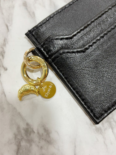 Black leather wallet with gold keychain on a marble surface