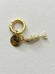Gold charm with a fish design on a light gray background