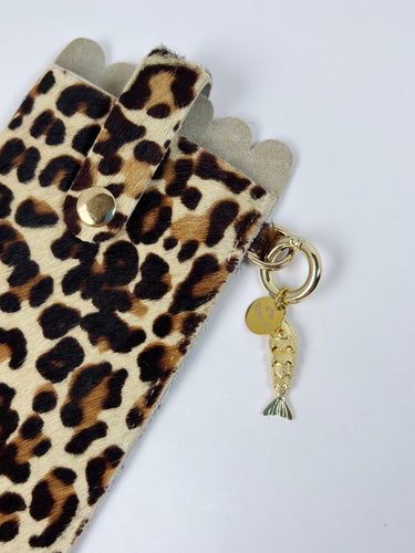 Leopard print phone case with a gold charm on a white background
