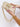 Beige handbag with gold chain held by a hand on a white background