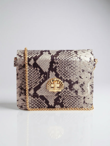 Snake print handbag with gold chain strap on a light gray background