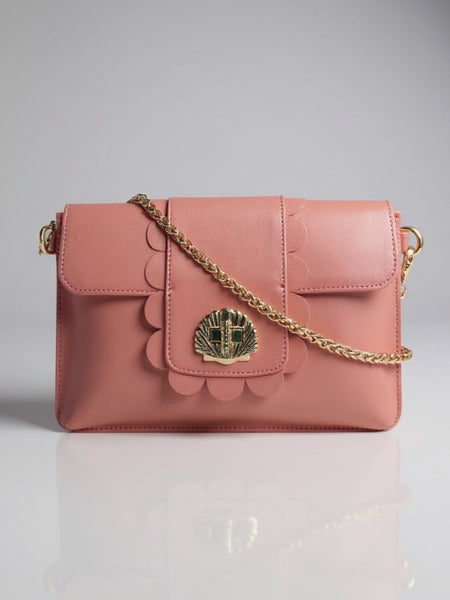 Pink handbag with gold chain and decorative emblem on a gray background